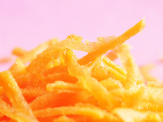 Finely grated carrots close-up (macro) on a pink background.