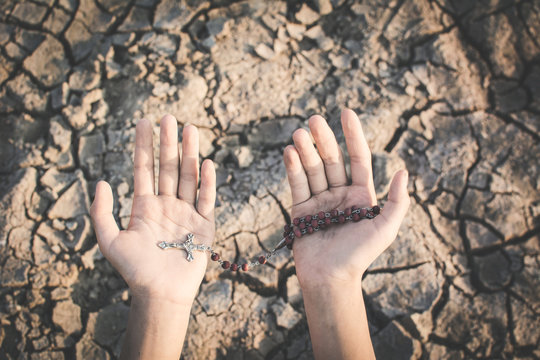 Human hands praying for the rain on cracked dry ground , Concept drought and shortage of water crisis, selective and soft focus
