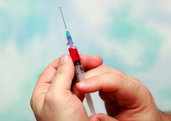 Hands push the red liquid out of the syringe