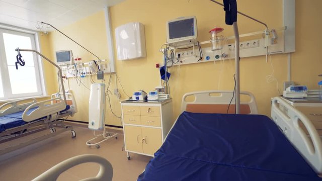 An empty hospital room with two beds, monitors, bedside tables and other equipment in it