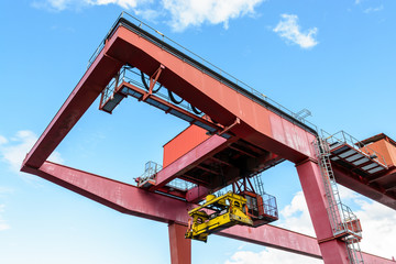 View from below of a red container gantry crane showing the spreader used for transloading...