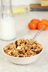 bowl of granola raisin almond cereal with bottle of milk