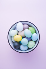 Colored eggs with pastelle tones inside a metallic bowl over a pink background, back lighted,  easter concept,holiday.