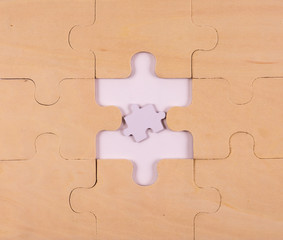A puzzle made of wood with a too small piece in the middle that not fit in.