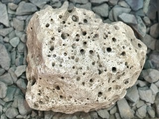 Big beige dotted stone on the gravel background
