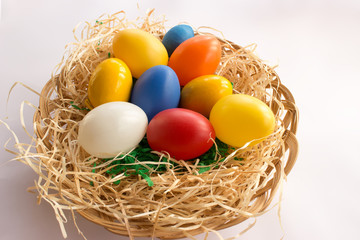 Colorful eggs on the straw in the wicker basket