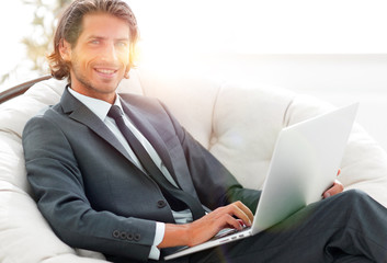 businessman with a laptop sitting in a stylish comfortable chai
