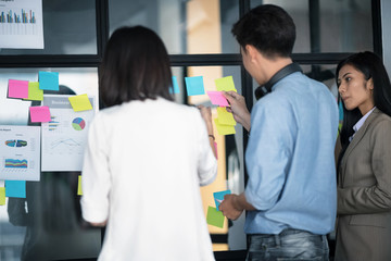 Obraz premium Businesspeople putting their ideas at sticky notes on window.