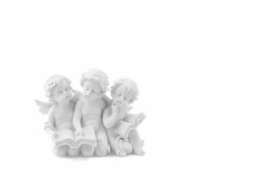 Three ceramic white angels read the book, dreaming and thinking. Isolated on white.