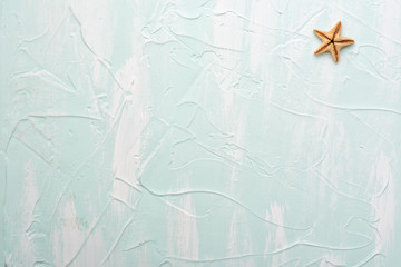 Fototapeta na wymiar Starfish on a blue surface. Minimalistic background for travel stories