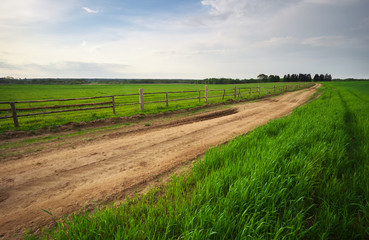 Rural environment with wooden fence beside the road. Spring Landscape