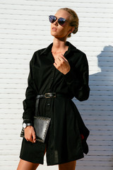 Trendy woman in sunglasses and black coat, posing outdoors