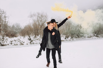 Naklejka premium Beautiful and joyful couple make modern pictures of colorful smoke in nature