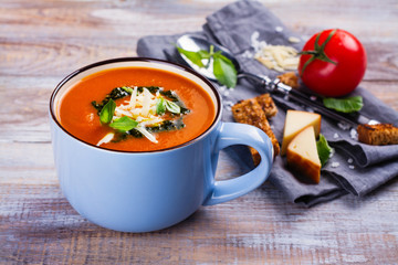 Tomato soup with pesto sauce and parmesan cheese in a ceramic cup