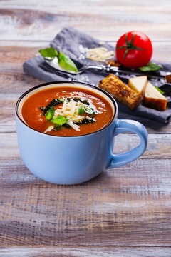 Tomato soup with pesto sauce and parmesan cheese in a ceramic cup