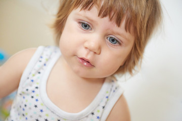 Portret of adorable baby girl with blue eyes and funny curly hair posing in studio
