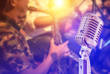 Close up retro microphone with musician playing saxophone on band in nigh concert background