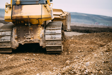 Close up details of bulldozer pushing earth and leveling ground on construction site