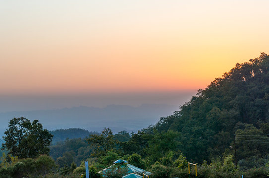 Dusk shot with beautiful orange sky, tree covered hills, a small shed. Perfect shot to showcase the beauty of the mountains in Uttarkashi india