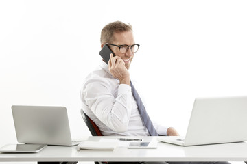 Businessman making call and using laptop