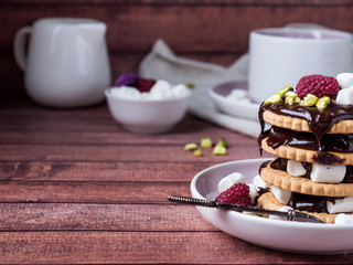 A sweet dessert of chocolate biscuit, raspberry marshmallow and a Cup of coffee on dark background.