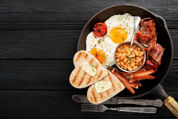 Full english breakfast with egg, sausage and bacon. top view