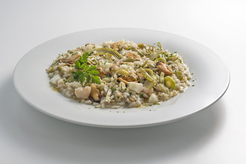 Round white dish of risotto with artichokes and seafood