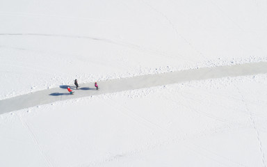 Aerial view of frozen sea. People are skating on the ice.