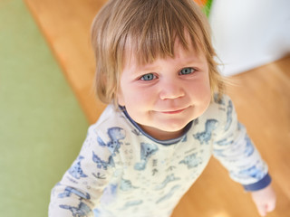 Portrait of cute adorable blonde Caucasian baby child girl with tears in her blue eyes, fairy tale sun light from above behind