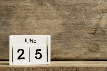 White block calendar present date 25 and month June on wood background