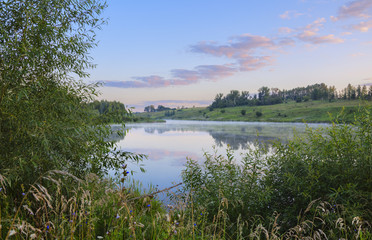 Summer morning.Foggy landscape with river.Beautiful clouds in sky.Fog over the water.Sunrise.River Krasivaya in Tula region,Russia. 
