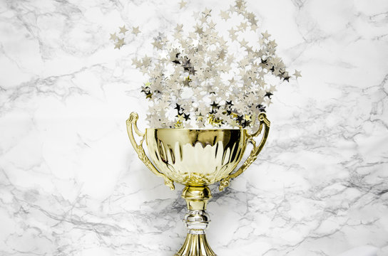 golden trophy on a marble table with stars confetti 
