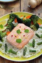 delizioso filetto di salmone cotto al vapore con verdure e riso su sfondo tavolo di cucina rustico