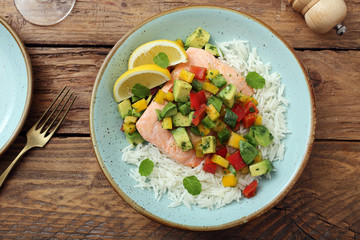 delizioso filetto di salmone cotto al vapore con verdure e riso su sfondo tavolo di cucina rustico