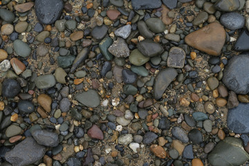 Rocky textures with round stones of different colors and sand aswell as dirt inbetween - beach seaside