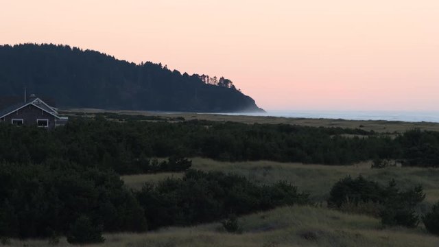 Looking south in Long Beach, Washington, over beach grass, a trail going through it it, towards Cape Disappointment and ocean at sunset.
