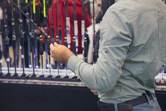 Man with a fishing rod in a fishing shop. Hobby