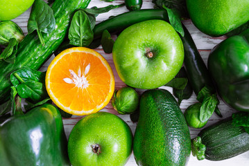 be different concept. orange surrounded by green fruits and vegetables. overhead view