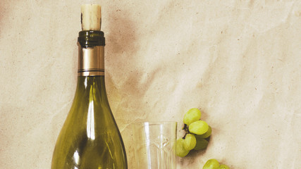 bottle of wine and a wineglass with a white grape brush on a light background