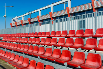 Empty red stands on a football stadium with a blue sky