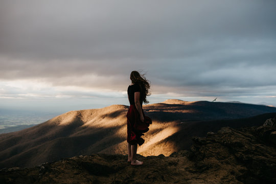 Young Woman Standing on Top of A Mountain at Sunset