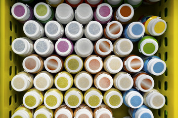 Artistic colorful jars with paint for art,  close to each other. The view from the top. In a yellow basket