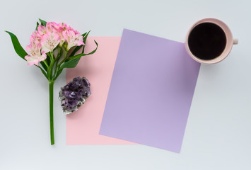 Blank Paper on White Desk Top Background with Cup of Coffee, Flowers, and Amethyst Healing Crystal Cluster