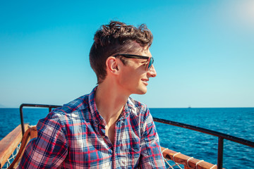 Fototapeta premium Young man enjoys the seaside view on a wooden yacht