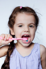 Little kid girl cleaning teeth by toothbrush, dental care concept.