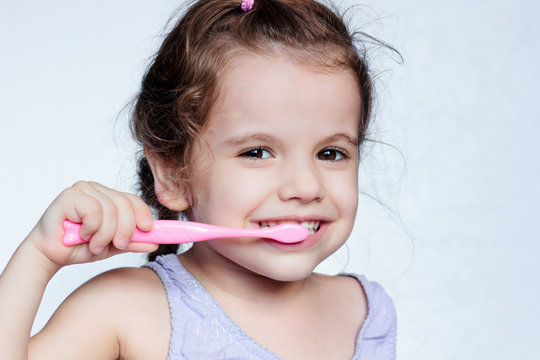 Adorable child girl cleaning teath by toothbrush.