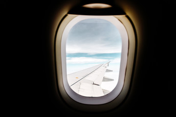 Fototapeta premium Commercial airplane wing seen through the window against blue sky