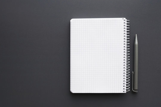 blank white notebook with pen over grey desktop