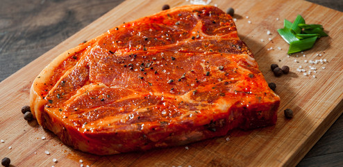 Raw marinated meat Steak for bbq, pork chop on a Wooden Chopping Board 