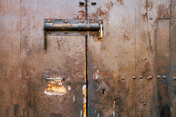Closeup of old wooden door broken with bolt and padlock